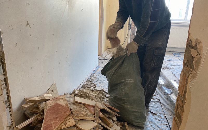 Strādnieki iznes būvgružus no dzīvokļa pa kāpņu telpu